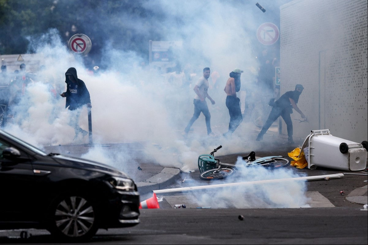 Individuals clash with police officers following the PSG team bus parade, near the Champs-Elysees avenue in Paris on June 1, 2025, a day after PSG won the 2025 UEFA Champions League final football match against Inter Milan in Munich. (Photo by Romain PERROCHEAU / AFP)