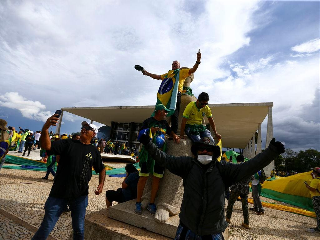 Criminosos sobem na estátua da Justiça, em frente ao edifício-sede do STF, em 8 de janeiro